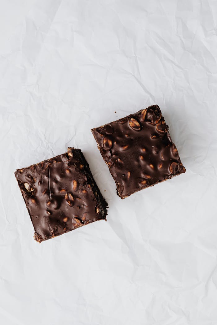 Close-up of two chocolate nut brownies on a crumpled paper background.